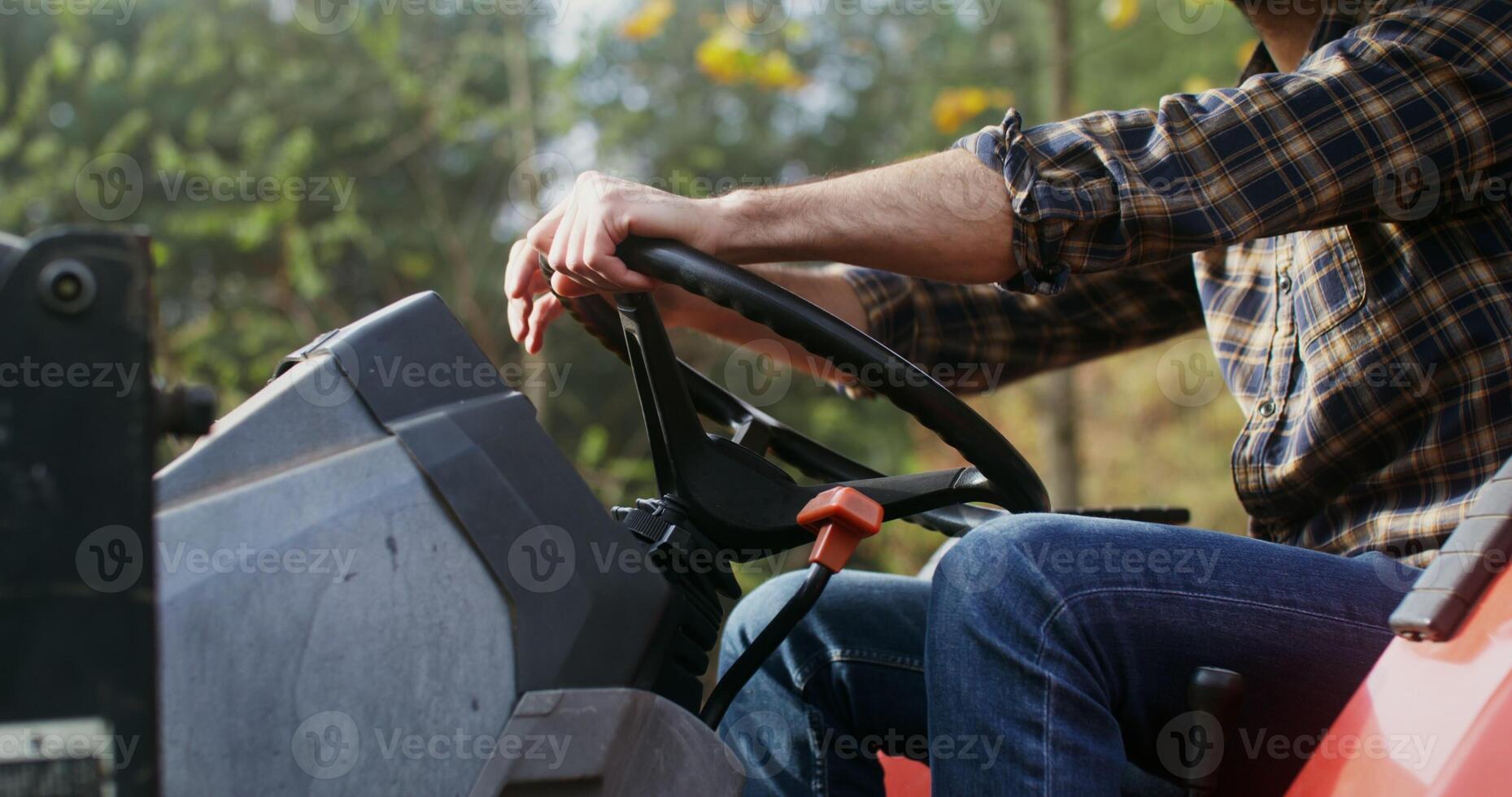 Young Caucasian man turned off the tractor engine and got out of it, having finished work in the field on a sunny autumn day photo