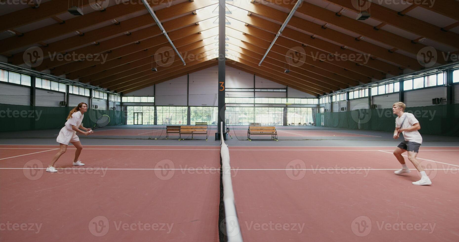 Tennis players play tennis with each other, throwing the ball over the net with a racket. Long throwing the ball over the net, playing on a steep tennis court photo