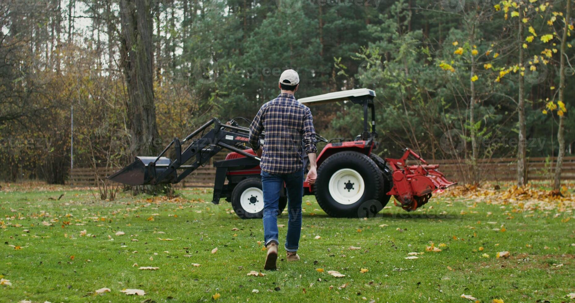 Male farmer getting ready to start work in the field on an autumn day, getting into a modern agricultural tractor and starting it photo