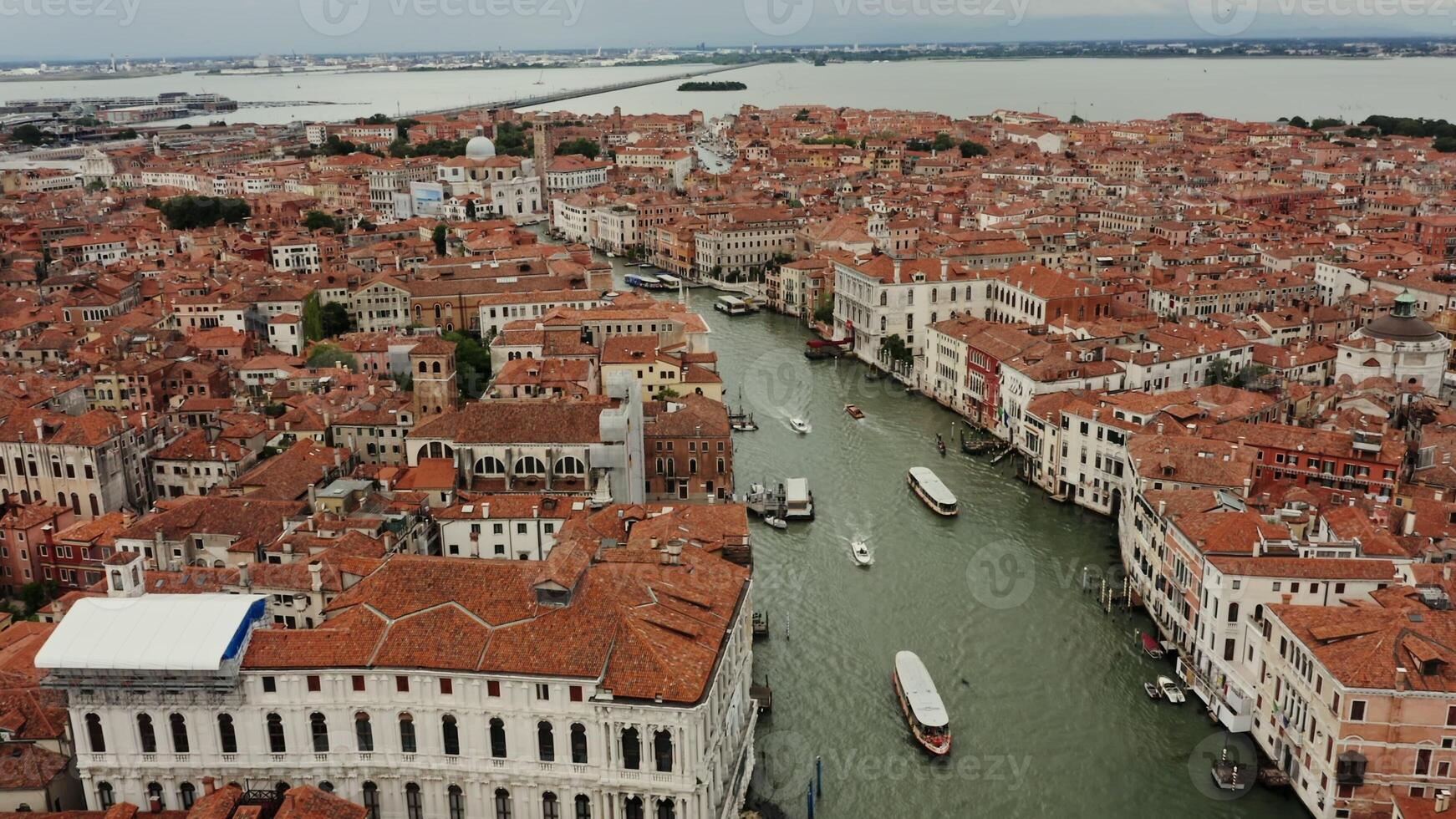 View of the Grand Canal with ships sailing along it and old traditional houses with orange roofs in the historic center of Venice. Italy. Drone photo
