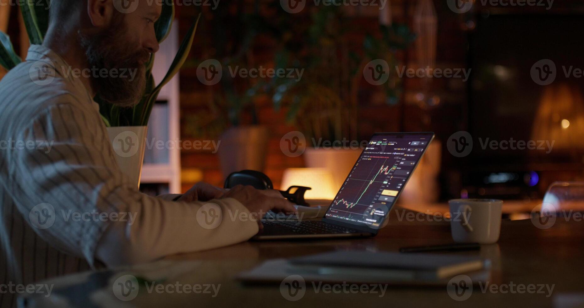 man participates in trading on the stock exchange, he uses a laptop while sitting at home photo