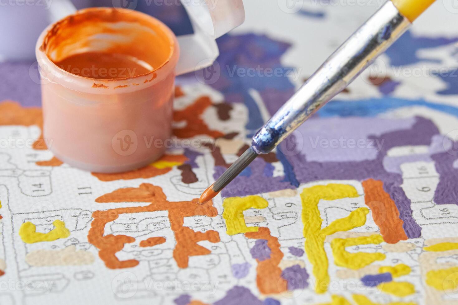 Close up of paint by numbers kit with brush and paint pots in vibrant colors. photo