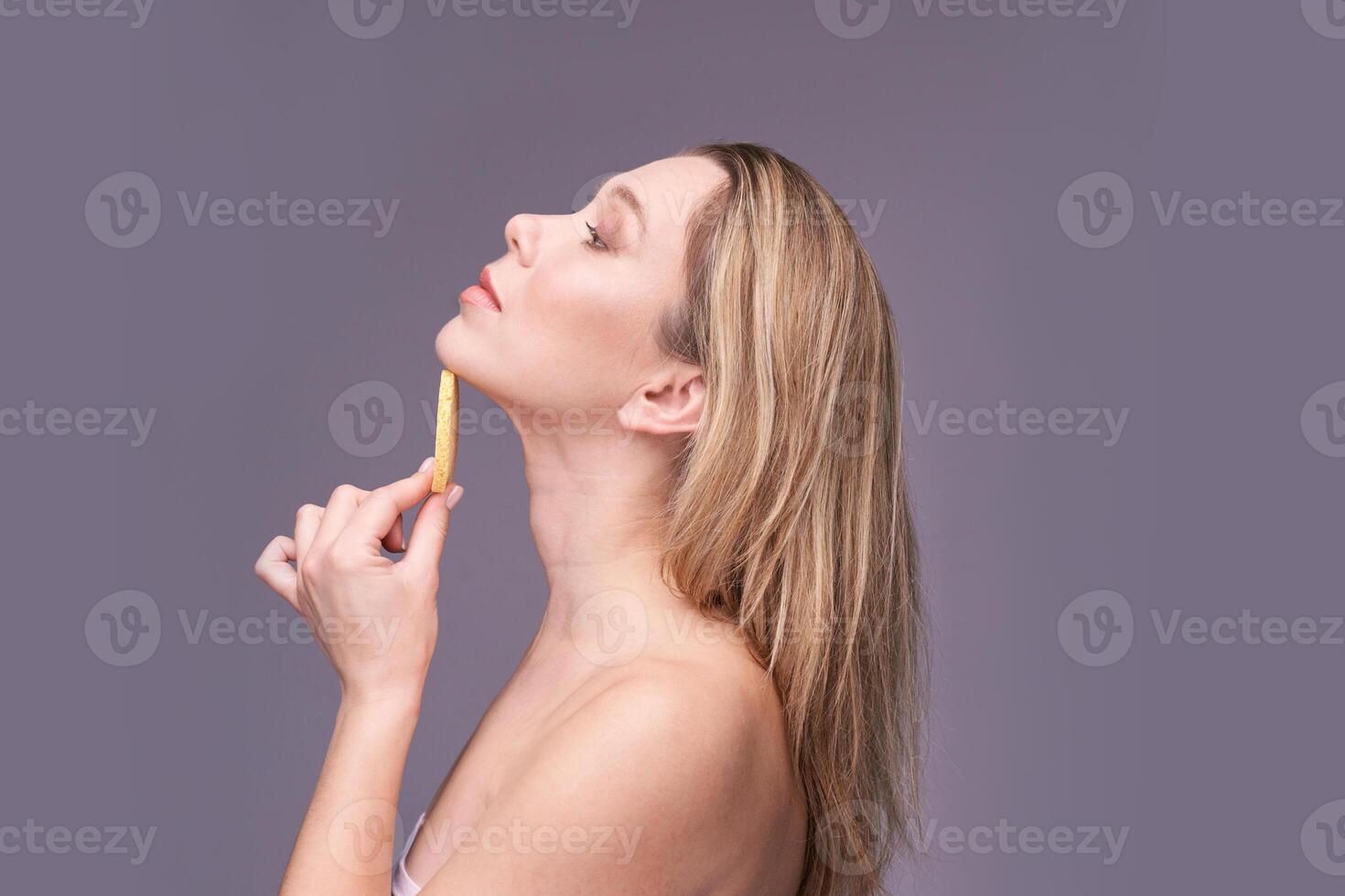 Caucasian young female examining neck contour with measuring tool on gray background. photo