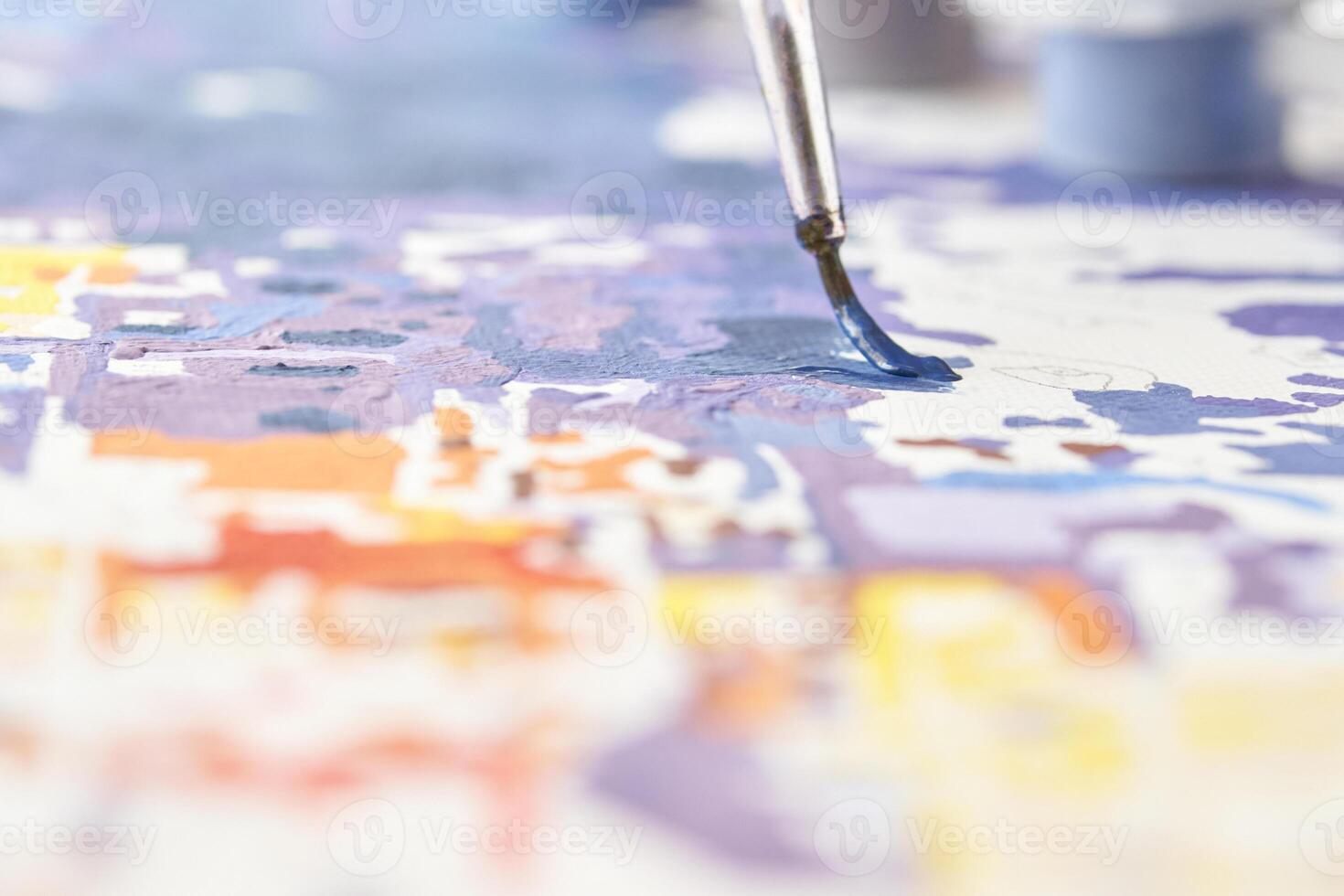Abstract painting in progress with focus on paintbrush and colorful details on canvas. photo