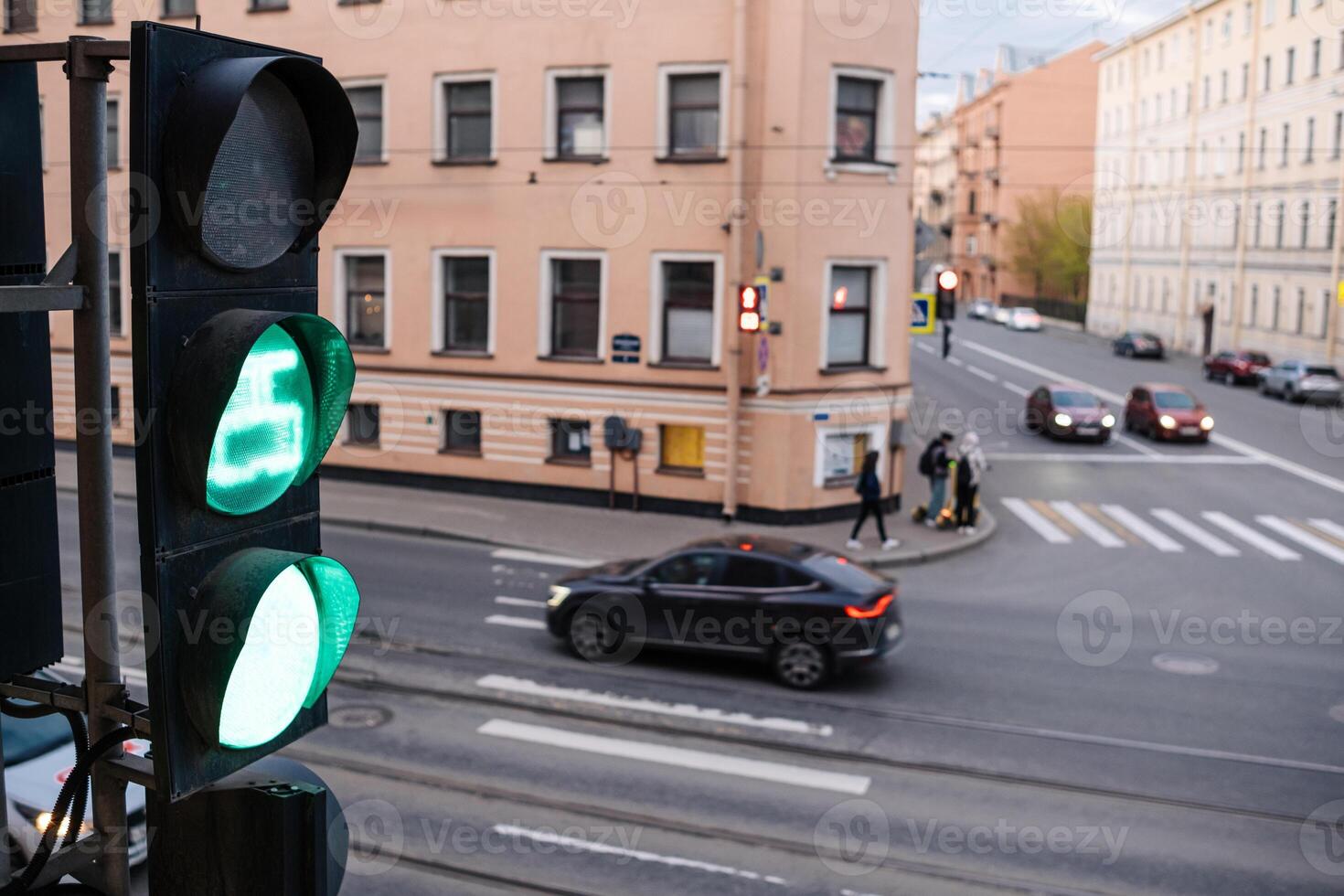 Green Traffic Light Guiding Vehicles at Urban Intersection in a Busy City Setting During the Late Afternoon photo