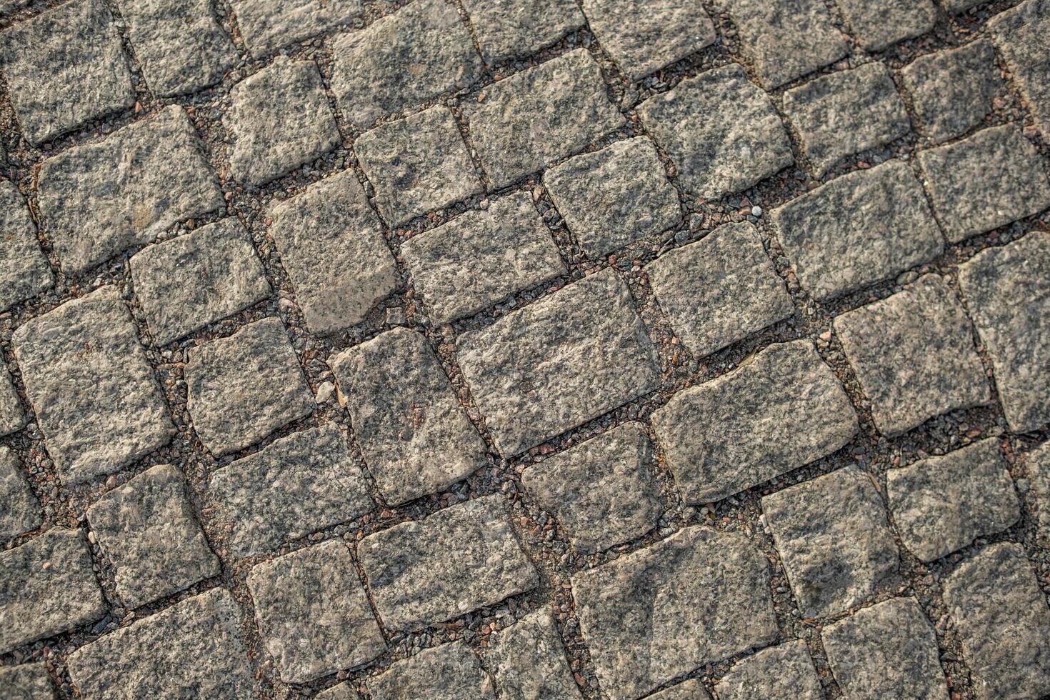 Uneven Cobblestone Pavement in Urban Setting Showcasing Intricate Stone Arrangement During Daylight Hours photo