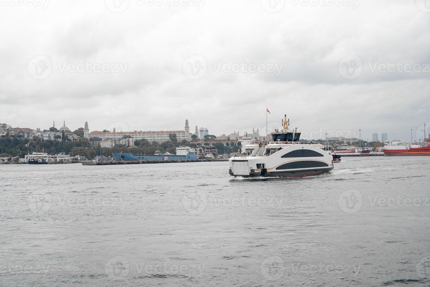 Bosphorus ferry cruising through calm waters with Istanbul skyline in the background on a cloudy day photo