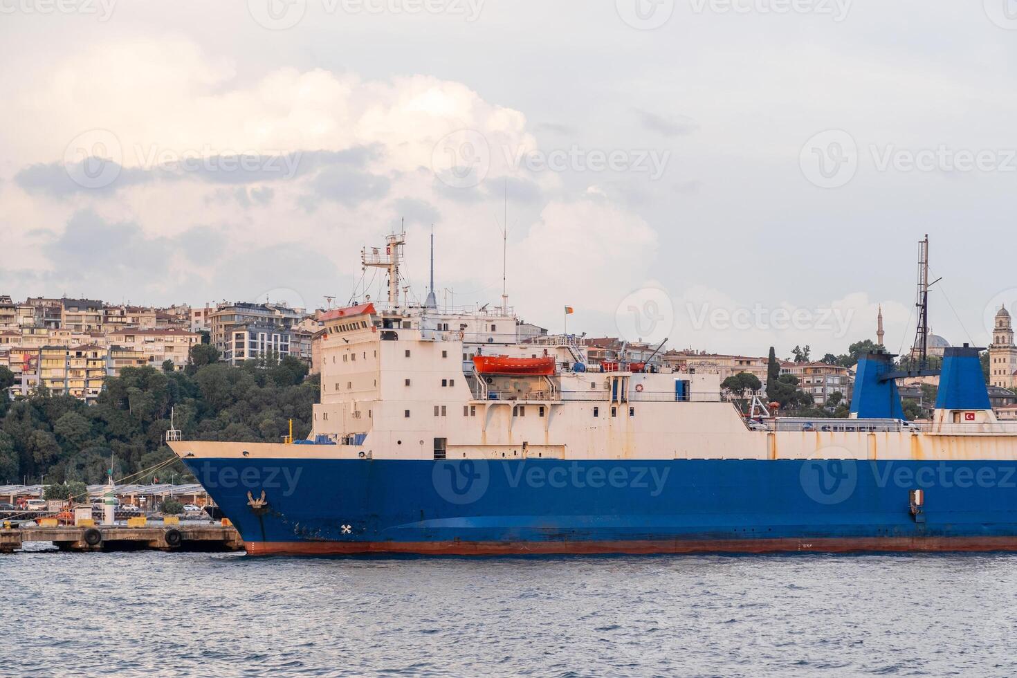 Cargo ship navigating the Bosphorus strait with city skyline in the background during late afternoon light photo