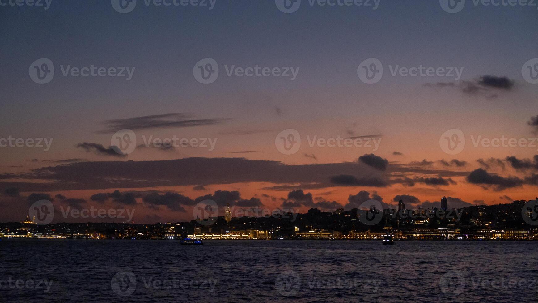 Sunset view over Bosphorus with city lights and clouds reflecting in the water photo