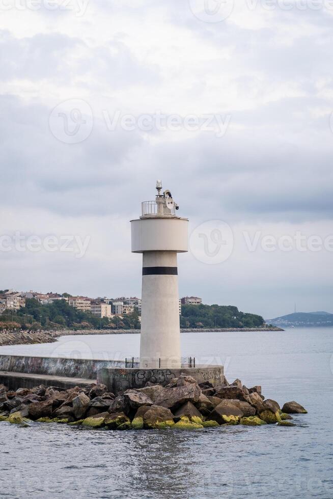 Bosphorus lighthouse standing tall against the coastal skyline on a cloudy afternoon with calm waters and rocky shore photo