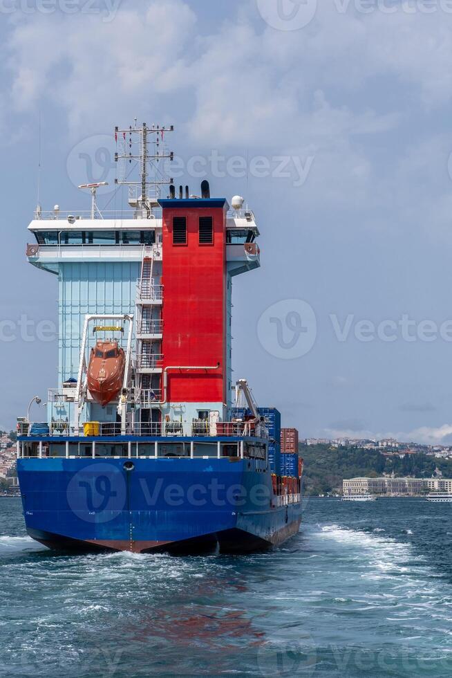 Large cargo ship navigates the Bosphorus Strait under clear skies in the afternoon light, showcasing maritime trade in a vibrant waterway photo