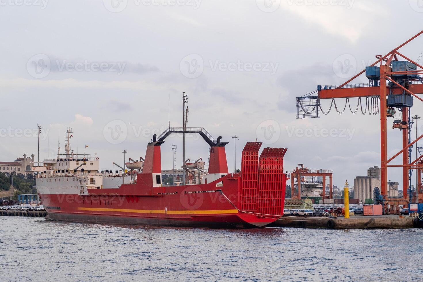 Red cargo ship docked near Bosphorus strait with cranes in the background during twilight hours photo