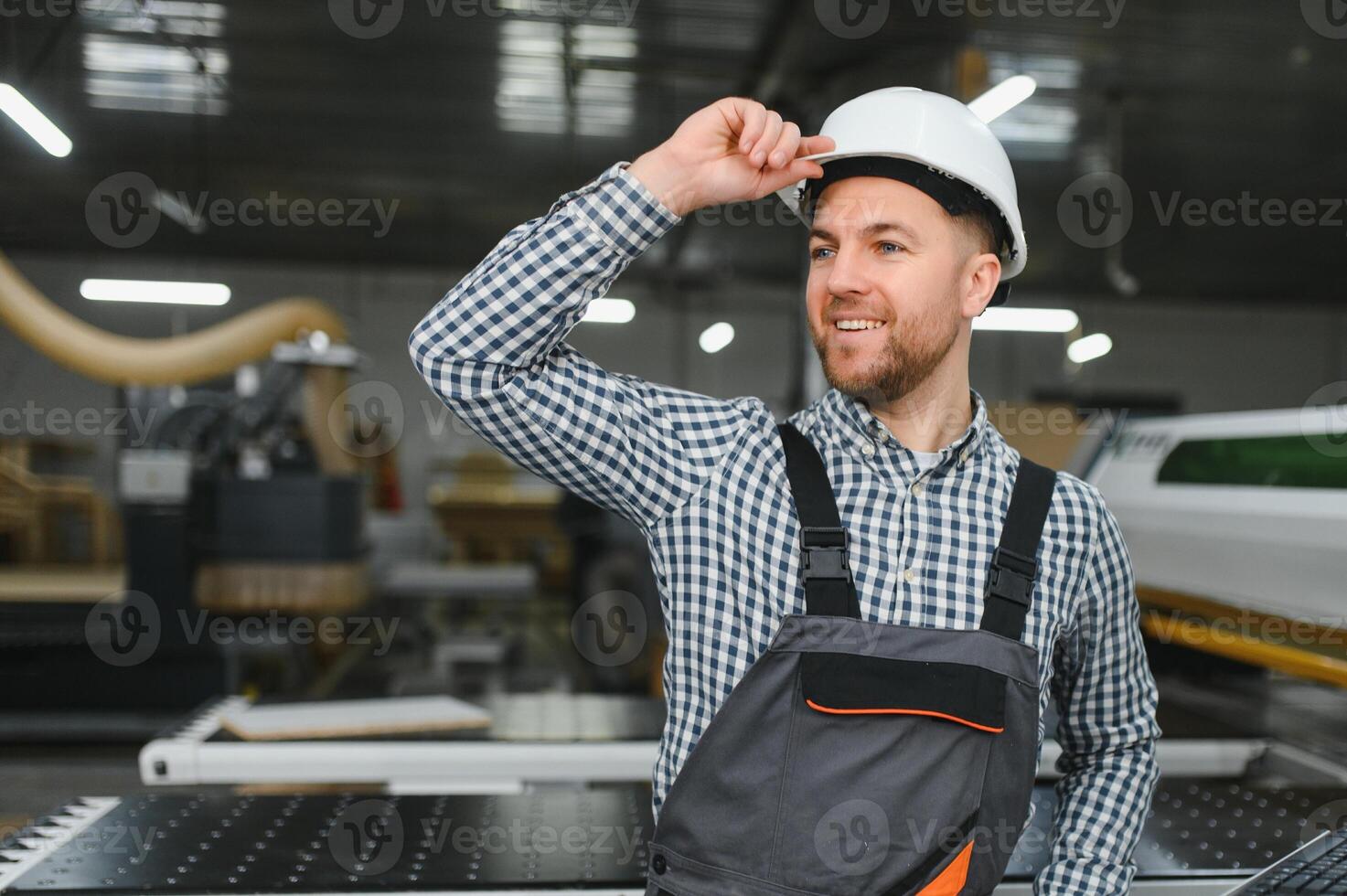 Furniture maker adjusting hardhat and smiling in factory photo