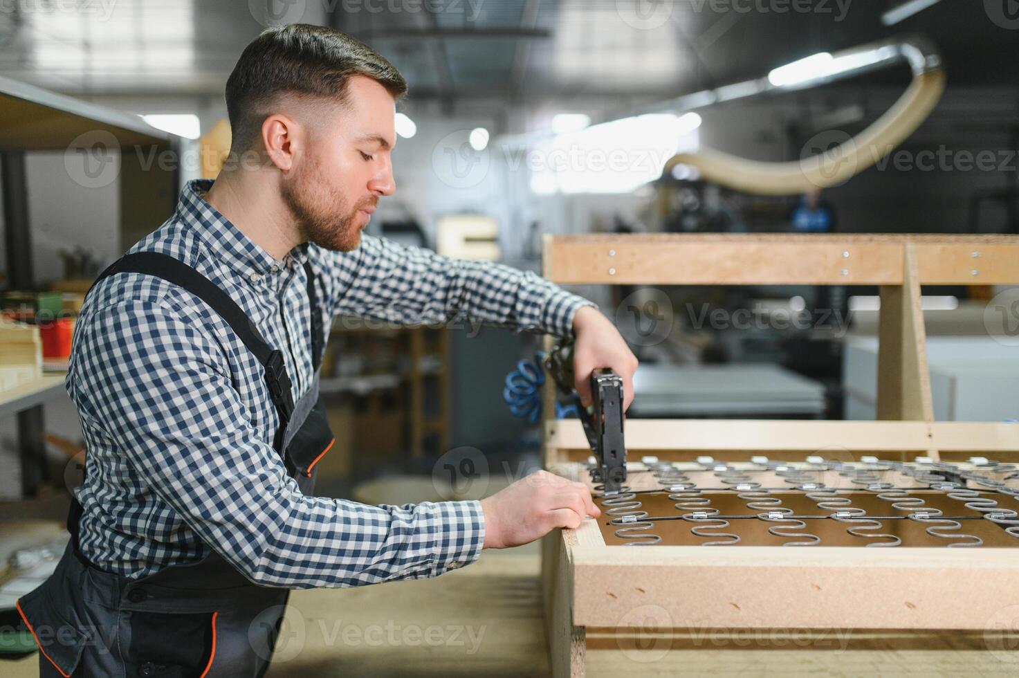 Carpenter using pneumatic stapler building sofa frame in furniture factory photo