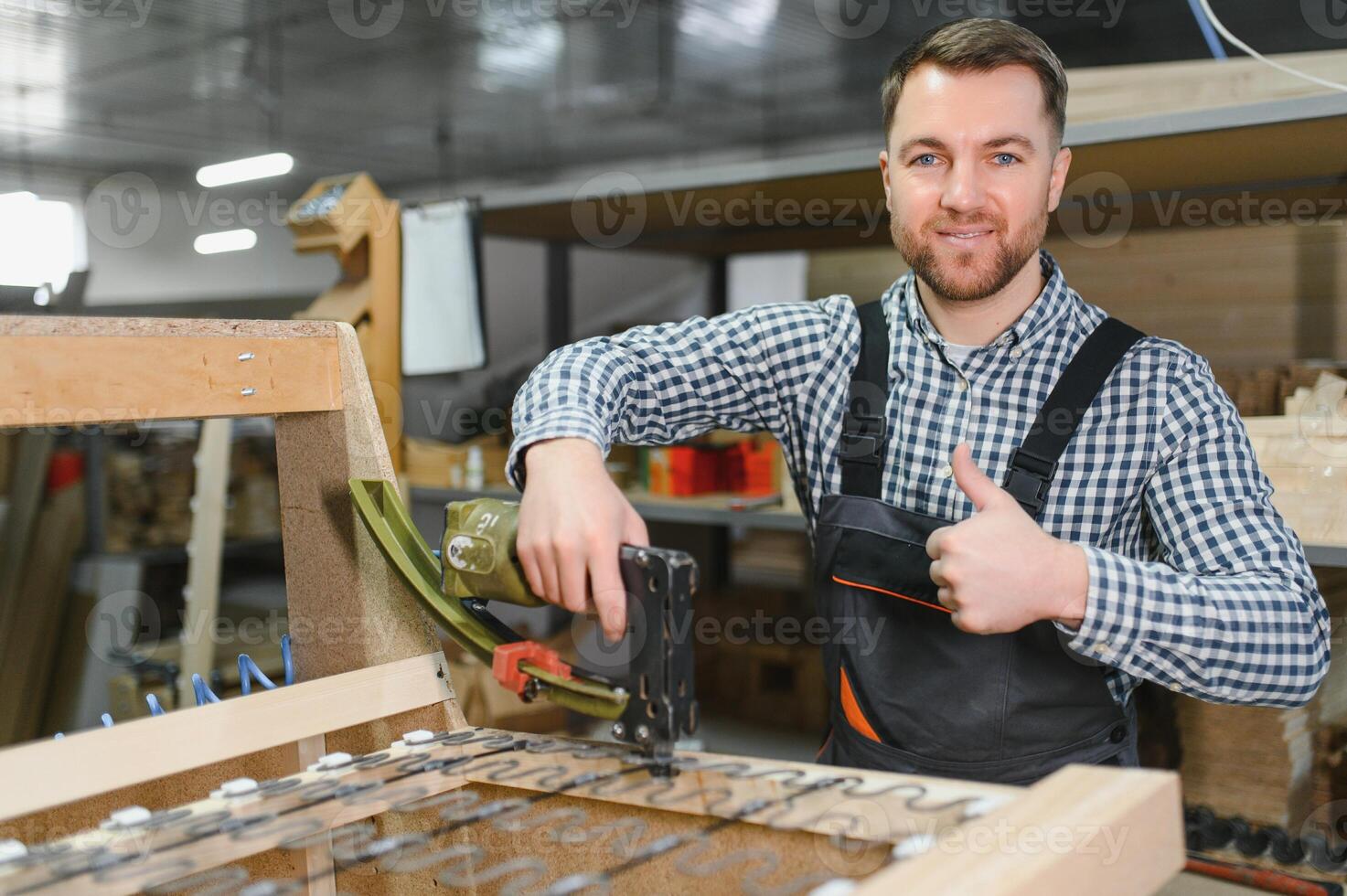 Carpenter working on sofa frame in furniture factory showing thumbs up photo