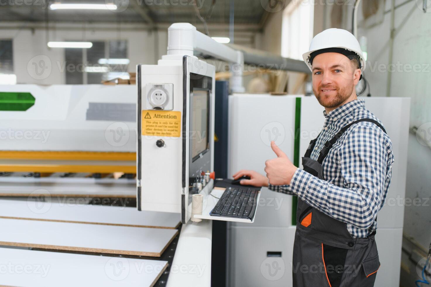 Carpenter operating cnc machine in furniture factory giving thumbs up photo