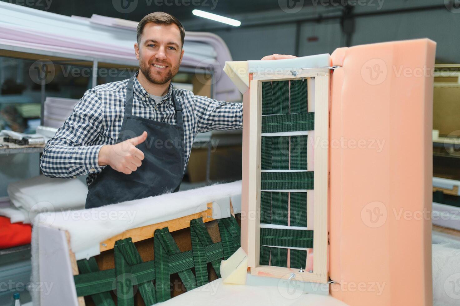 Carpenter showing thumb up near sofa frame during furniture production photo