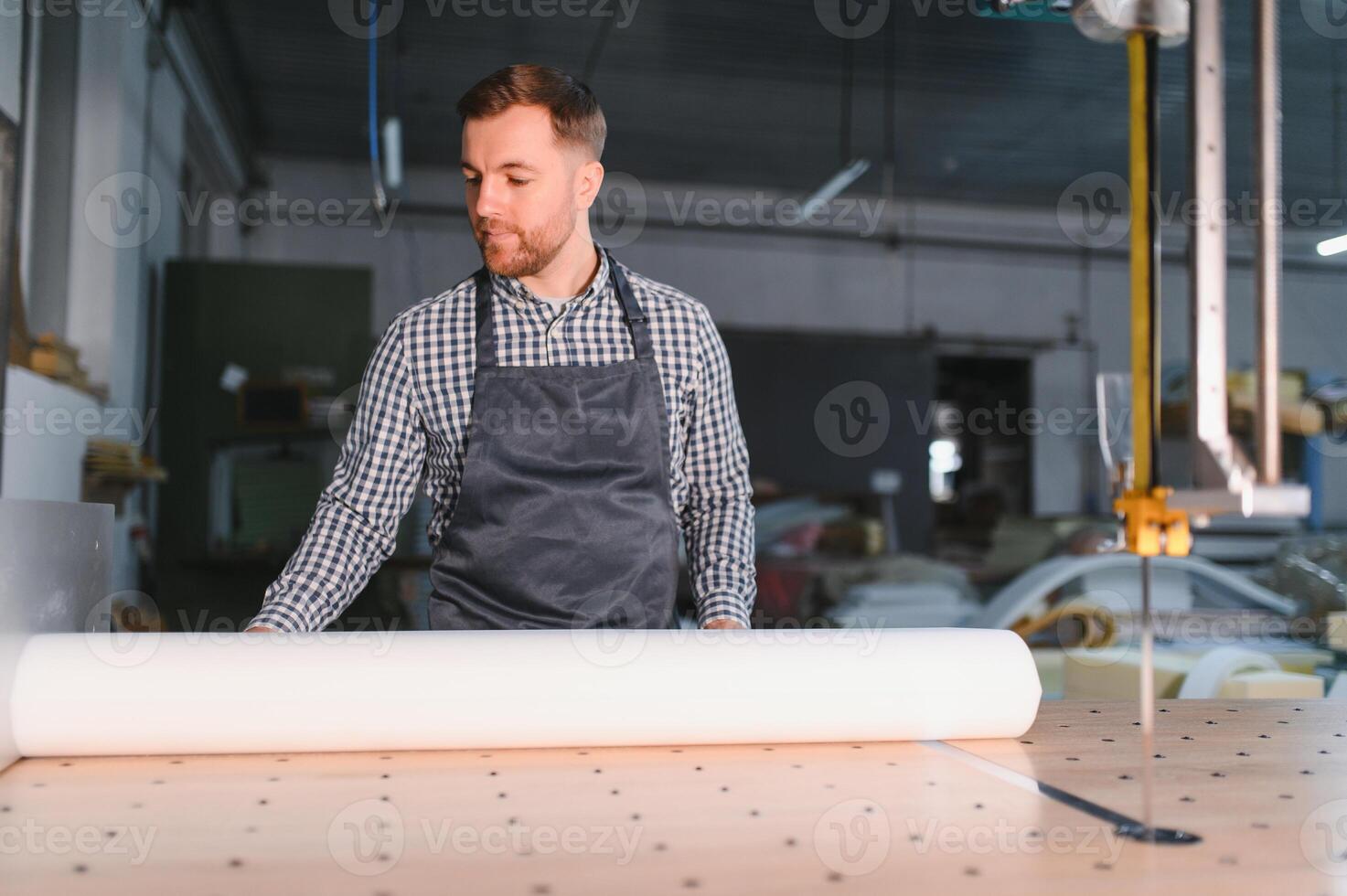 Carpenter unrolling fabric on workbench in furniture factory photo