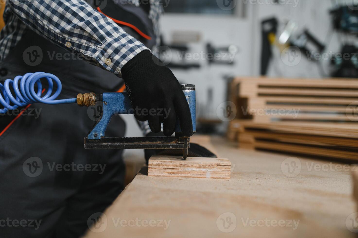 Carpenter using pneumatic nail gun in furniture factory photo