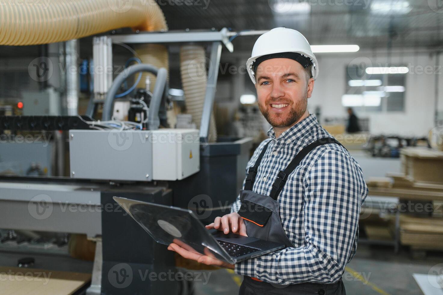 Furniture maker operating cnc machine with laptop in factory photo