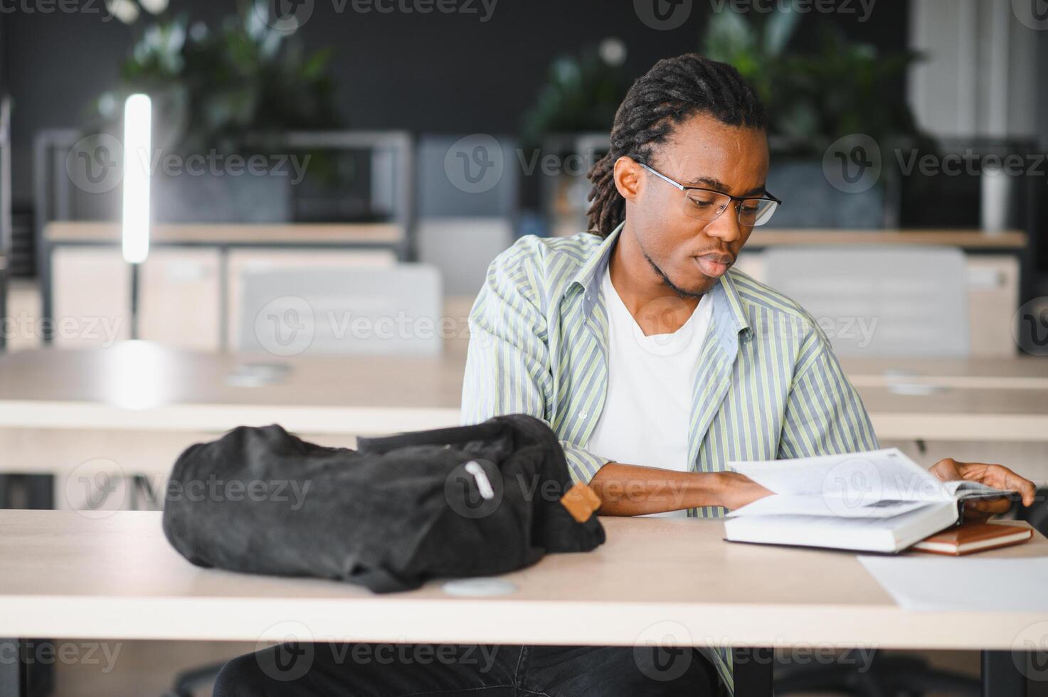 Focused university student studying textbook in library photo