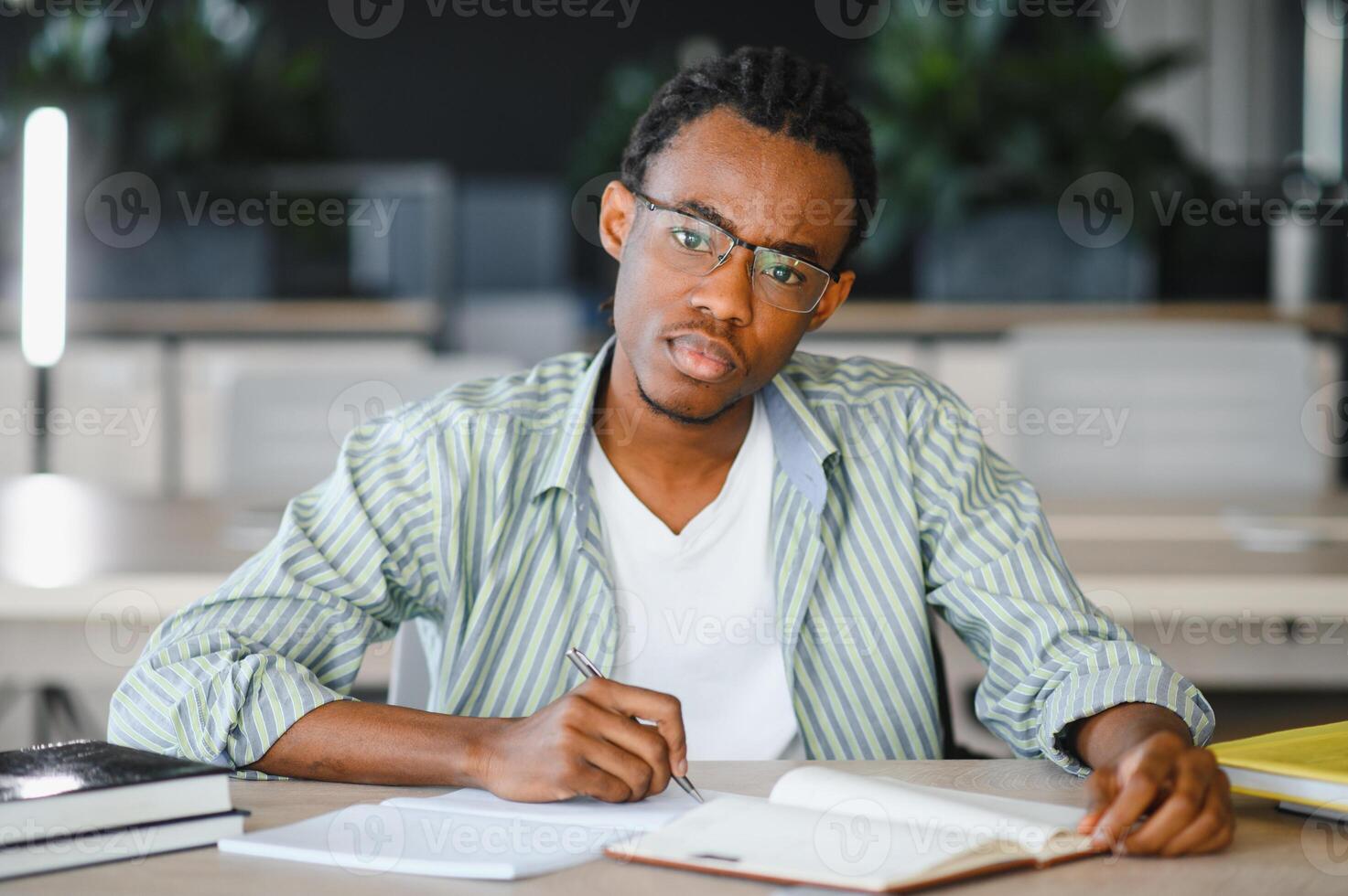 Focused university student taking notes and studying in library photo