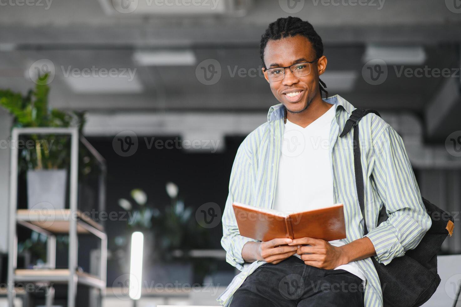 Smiling african american student reading book in university library photo