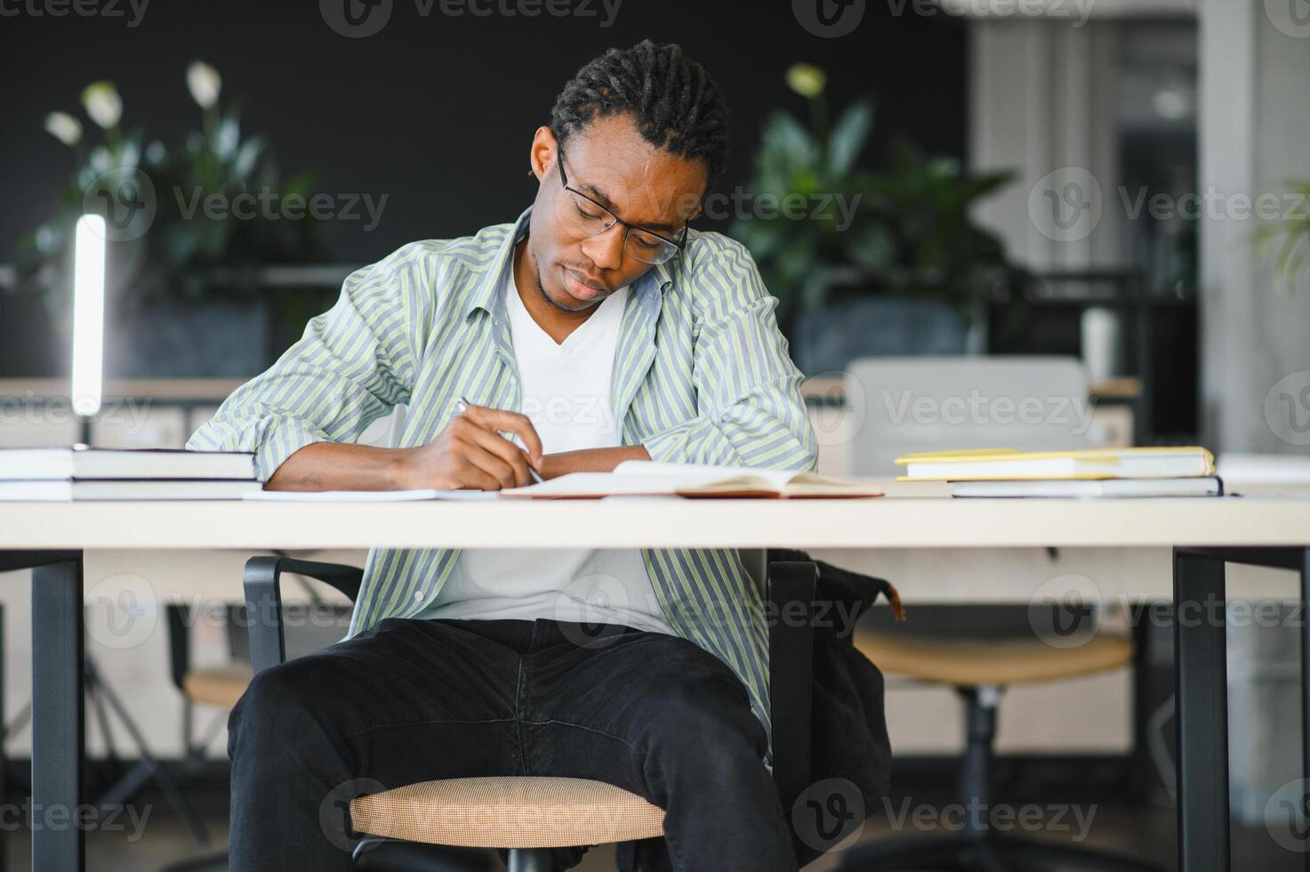 Focused university student studying and taking notes in library photo