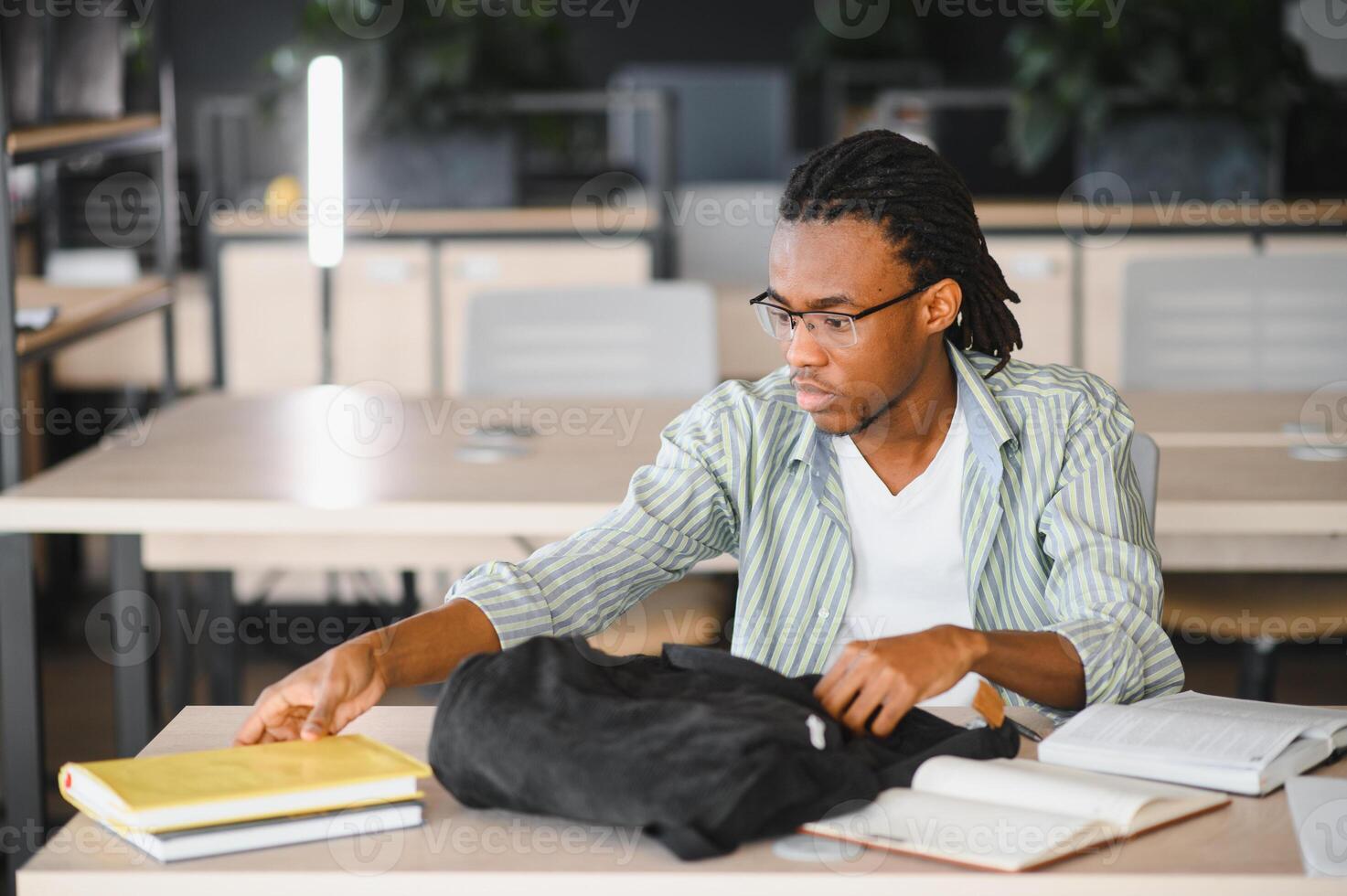 University student taking book from backpack in library photo
