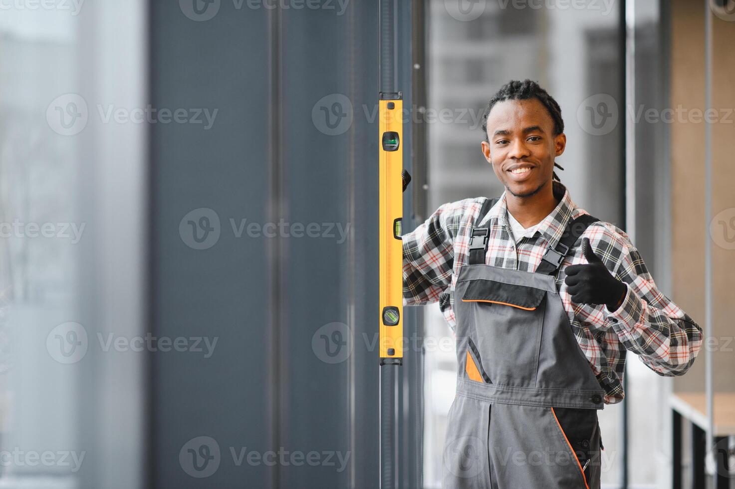 Construction worker checking vertical alignment with spirit level and gesturing thumbs up photo