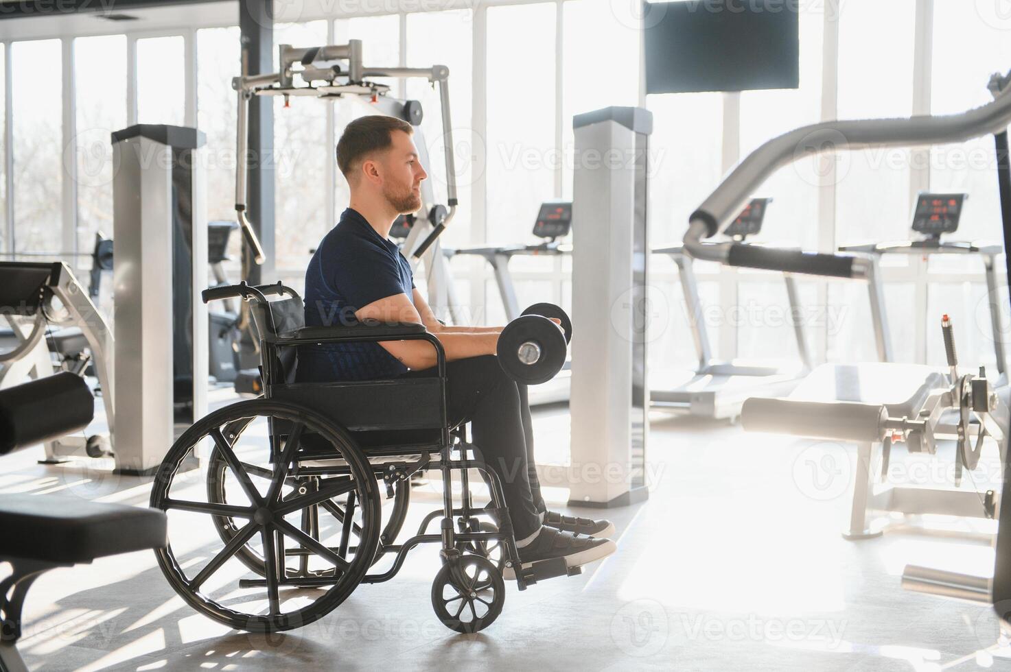 Man with disability lifting weights in a wheelchair at the gym photo