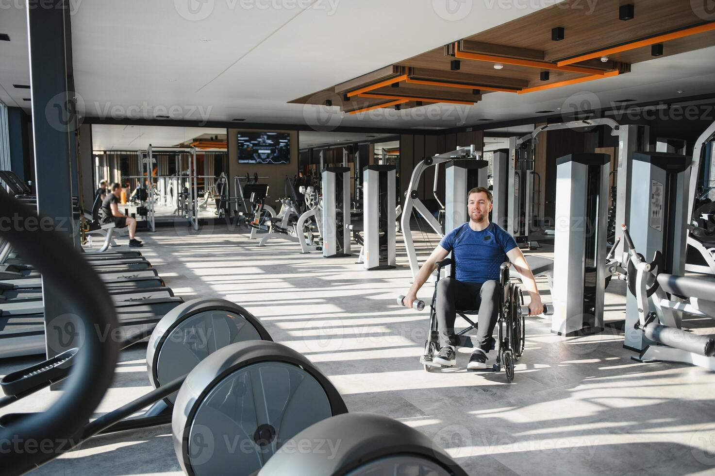 Man in wheelchair lifting weights, exercising in accessible modern gym photo