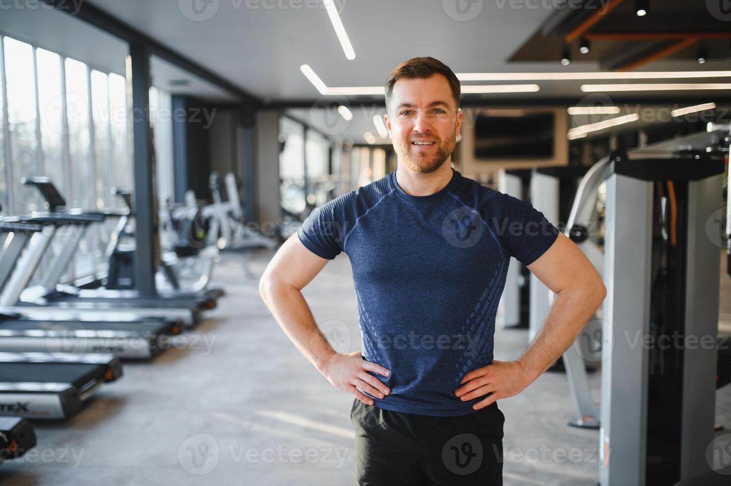 Confident fitness instructor posing in modern gym photo