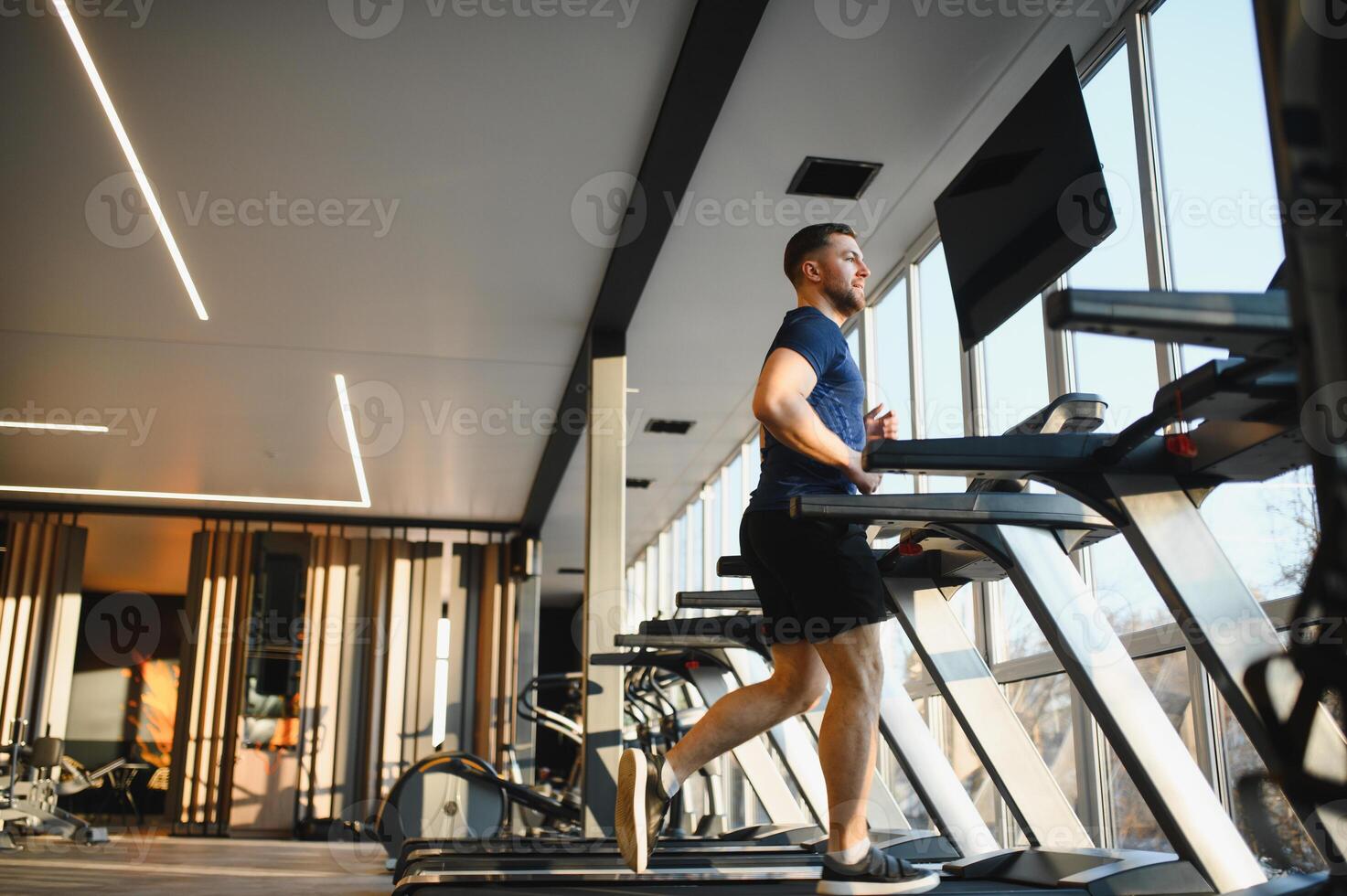Determined man running on treadmill during rehabilitation in modern gym photo