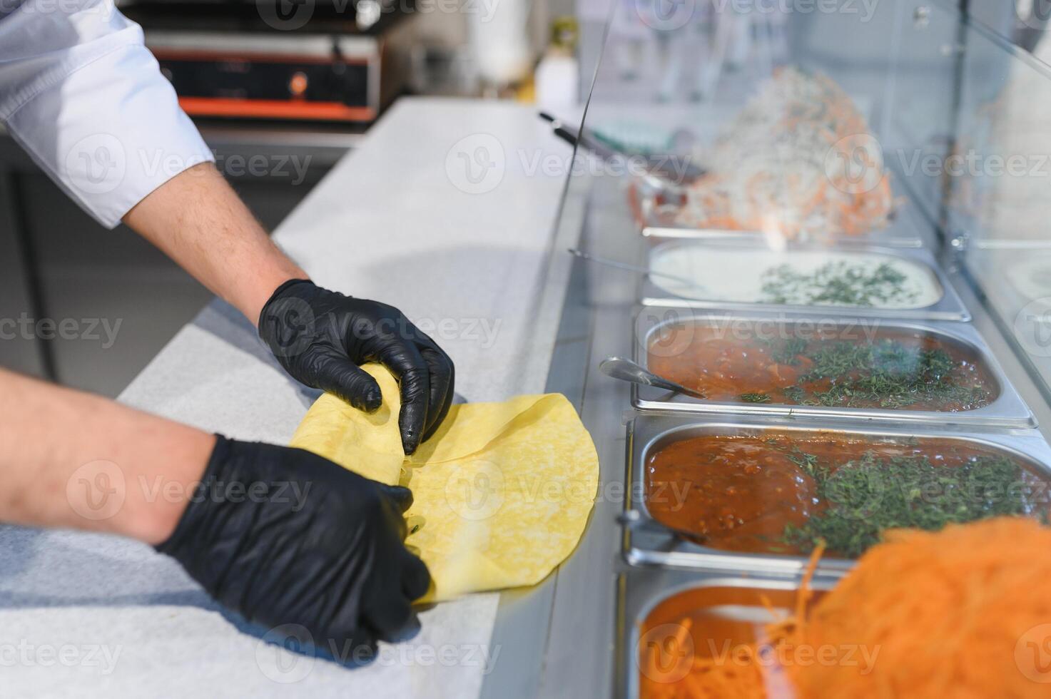 Chef preparing shawarma or kebab using pita bread and ingredients photo