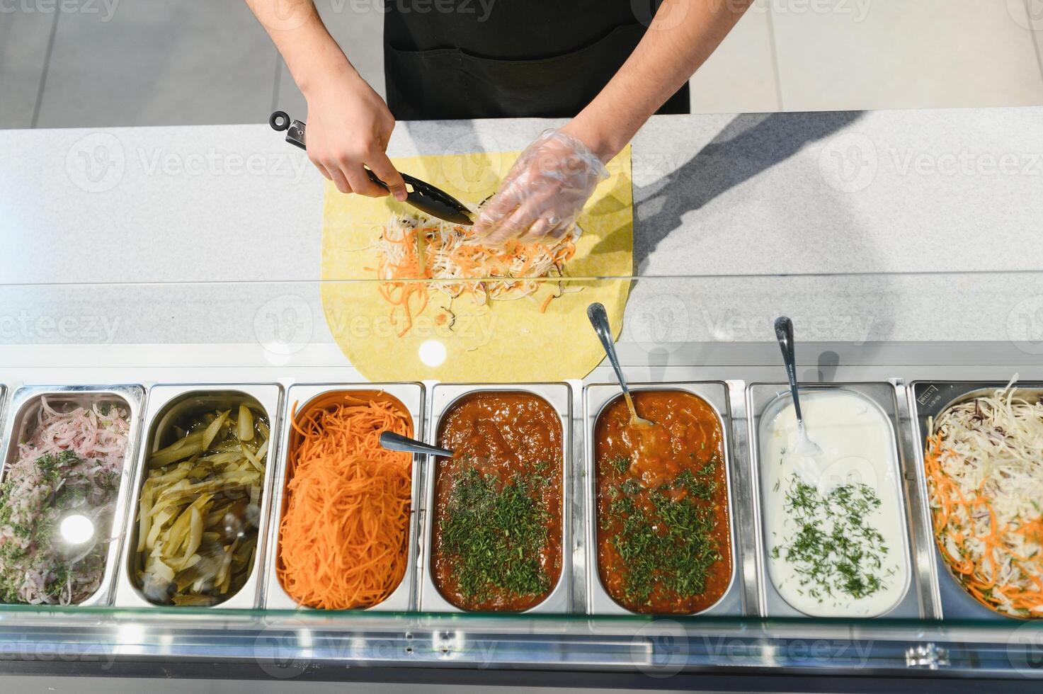 Chef preparing shawarma or kebab with various ingredients in trays photo