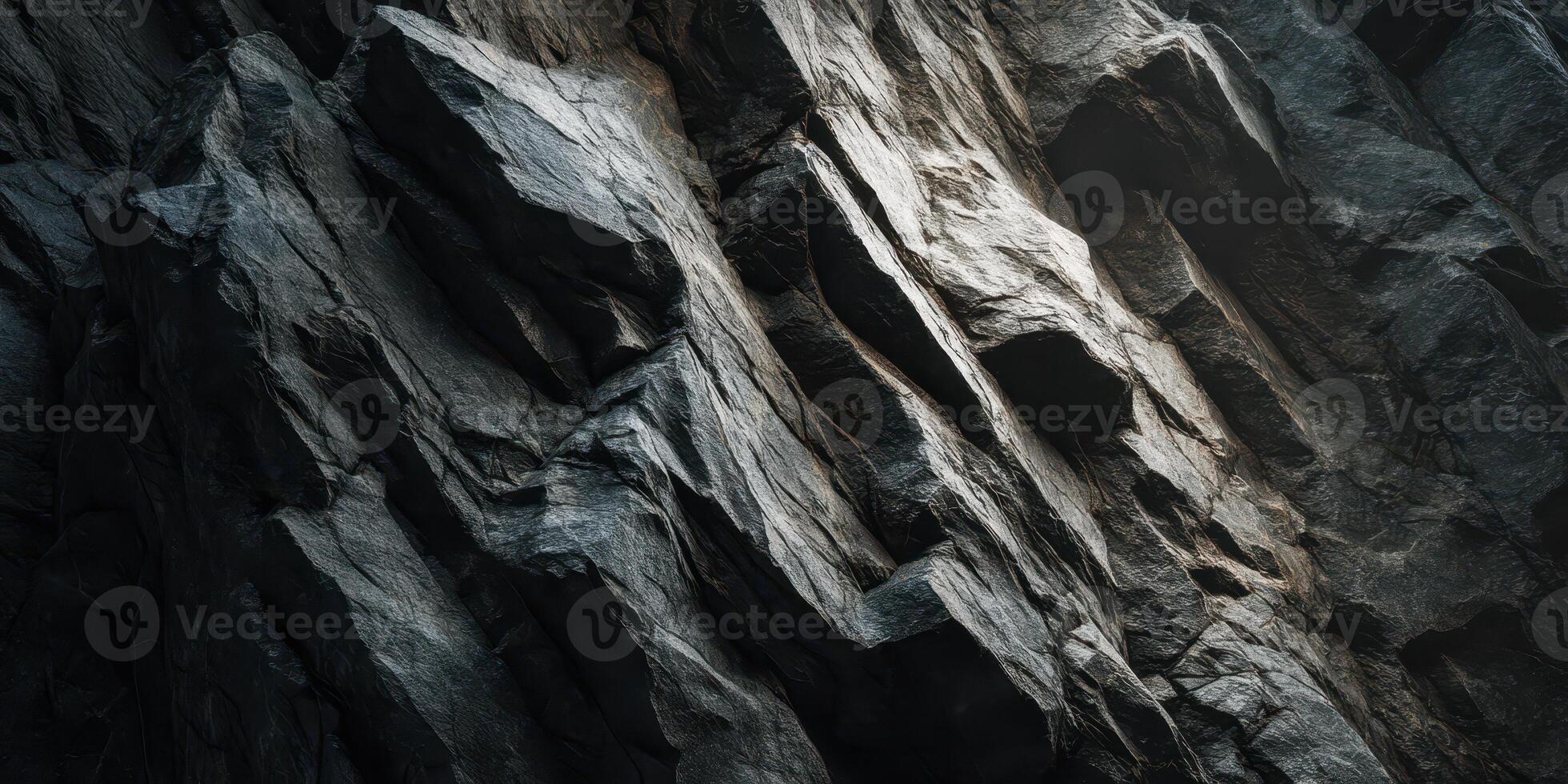 Close up of rugged dark textured rock surface with light photo