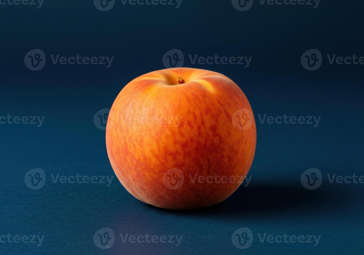 A close up shot of a perfectly ripe peach on a striking blue background. photo