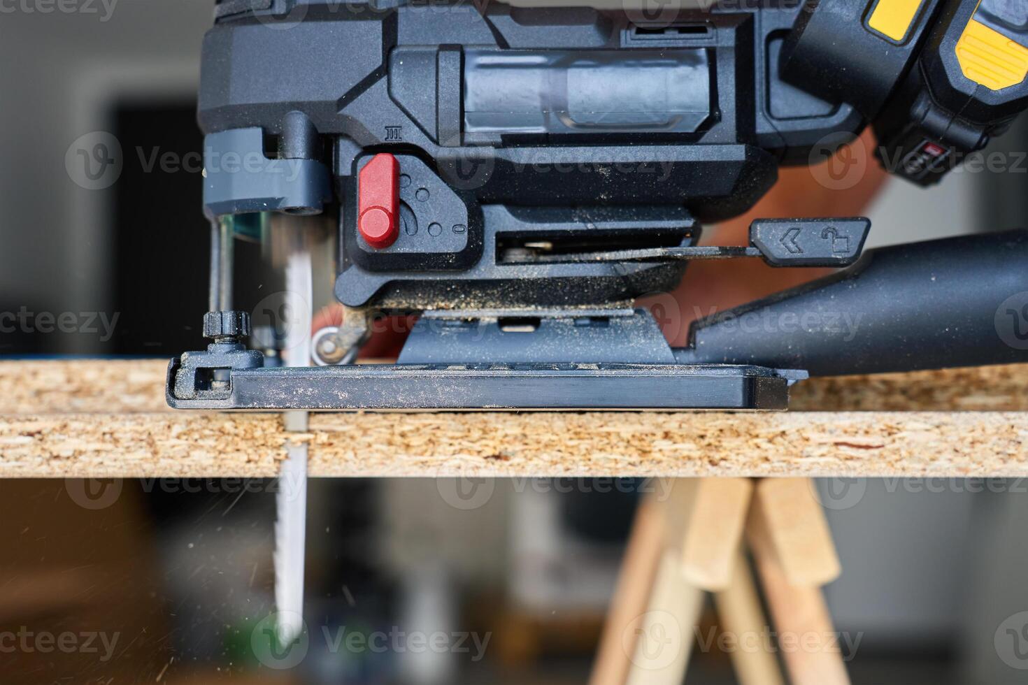 Electrical handheld jigsaw cutting wooden board in workshop. Work tools for manual labor. Carpentry and woodworking concept photo