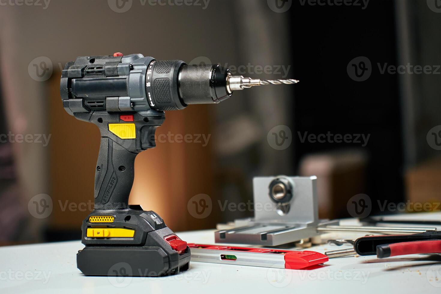 Electric cordless drill with bits and hand tools on workbench in workshop photo