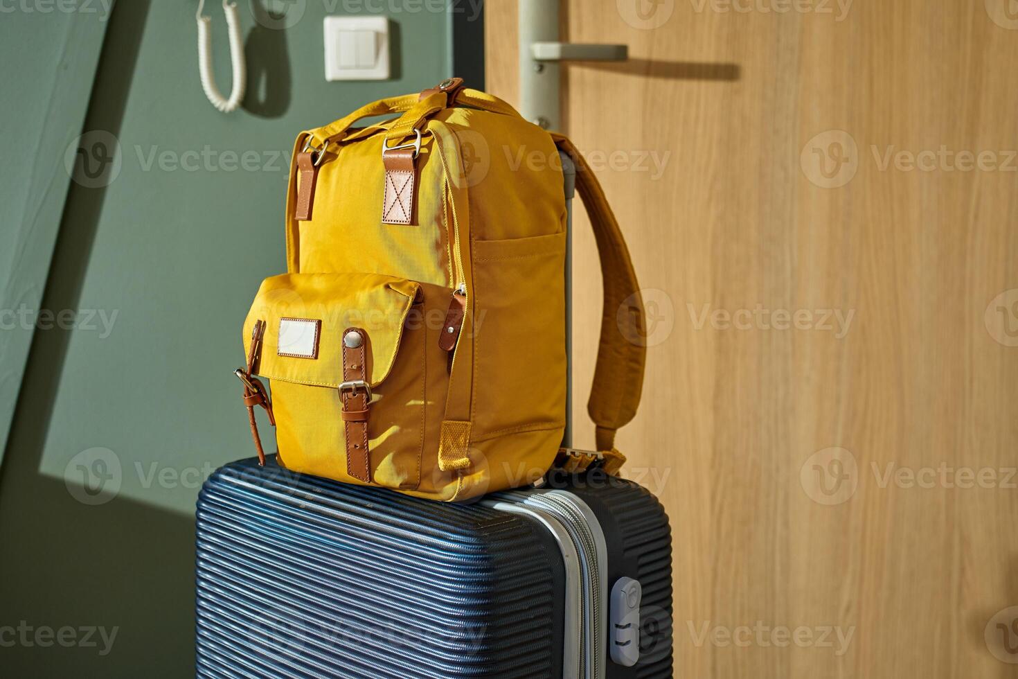 Packed suitcase and yellow backpack stand by door. Luggage ready for departure. Preparation for trip or travel photo