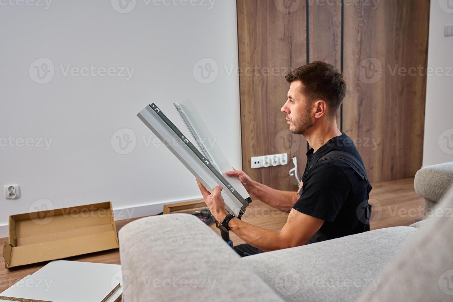 Man assembles furniture, examining white panel and surrounded by tools photo