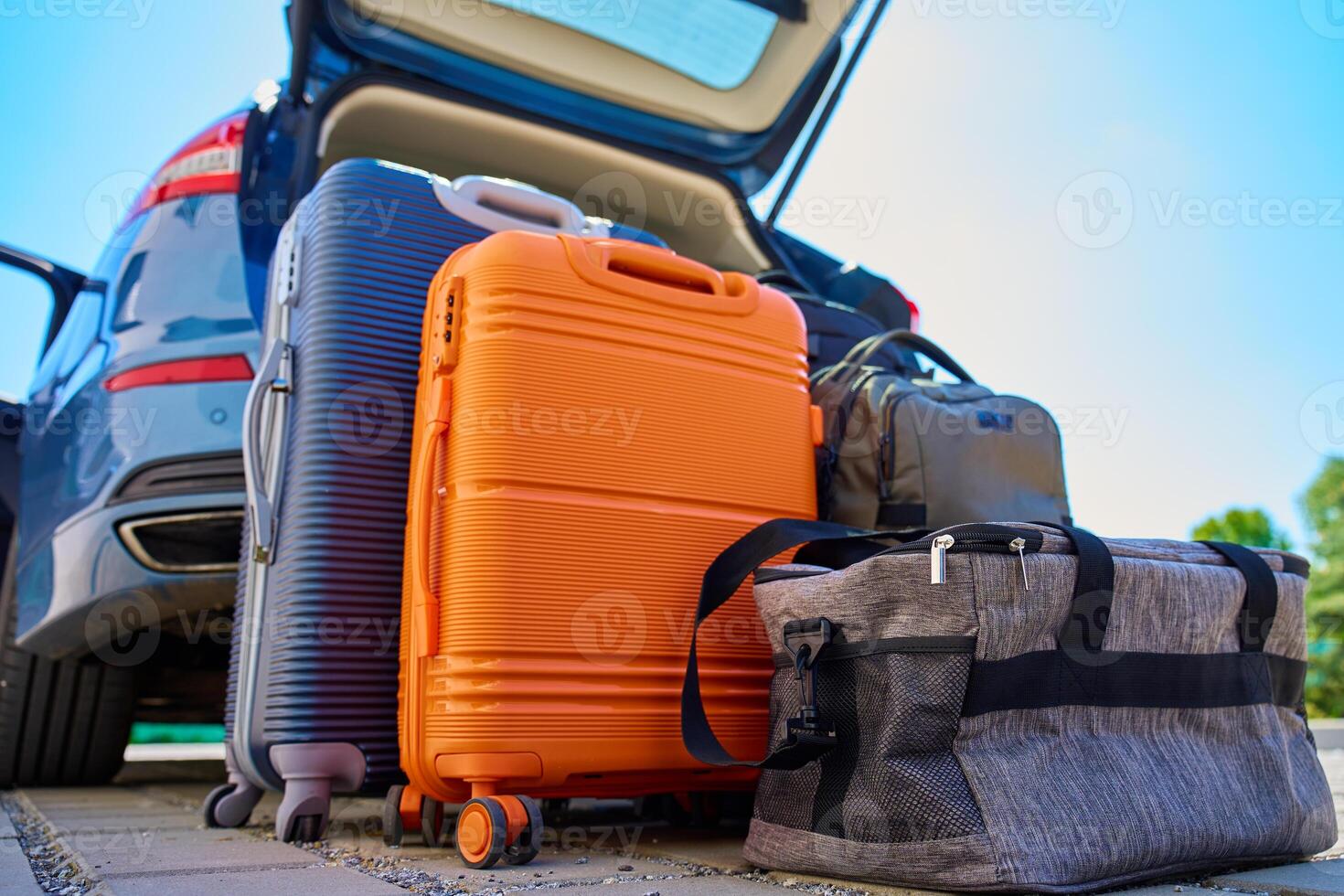 Suitcases and bags in front of open car trunk, standing on pavement near suburban house. Luggage ready for loading in vehicle before travel or moving. Concept of relocation or road trip photo