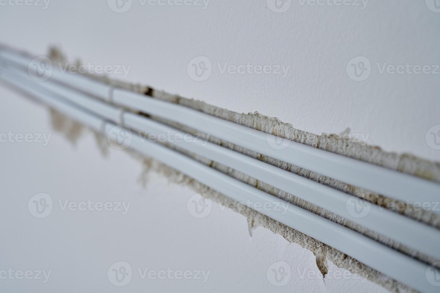 Close-up of white electrical cables embedded in wall groove during wiring installation. Concept of electrical work, construction or renovations photo