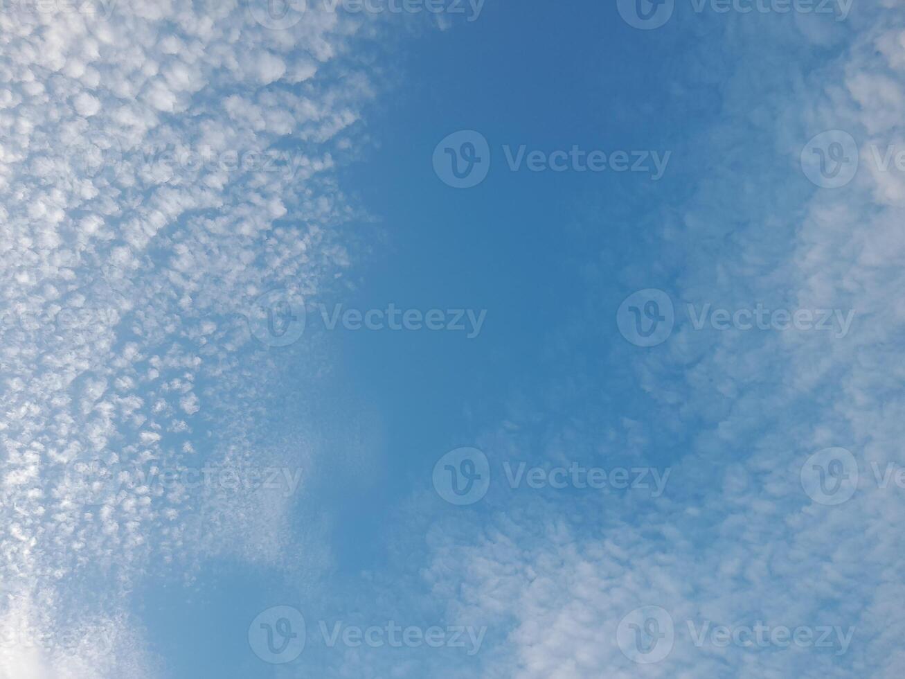 A calm sky filled with scattered white clouds under a clear blue backdrop, creating a peaceful and serene atmosphere. photo