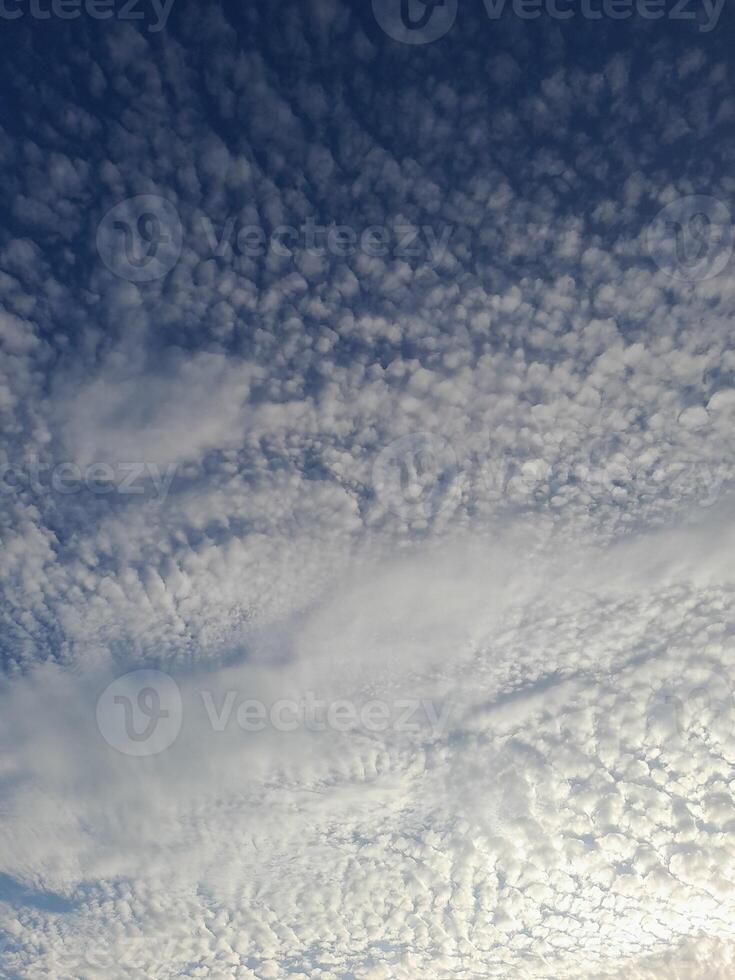 Soft, scattered clouds stretch across a calm blue sky, creating a peaceful and serene morning atmosphere photo