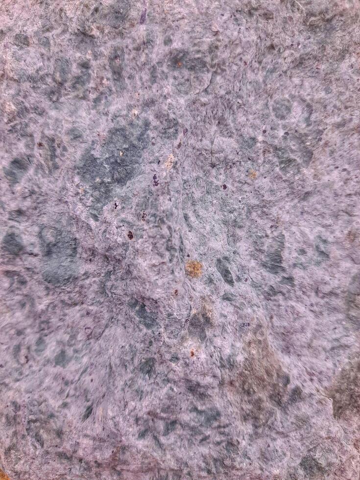 Rough natural stone texture with a mix of gray, violet, and earthy tones, perfect for backgrounds, construction, or design elements. photo