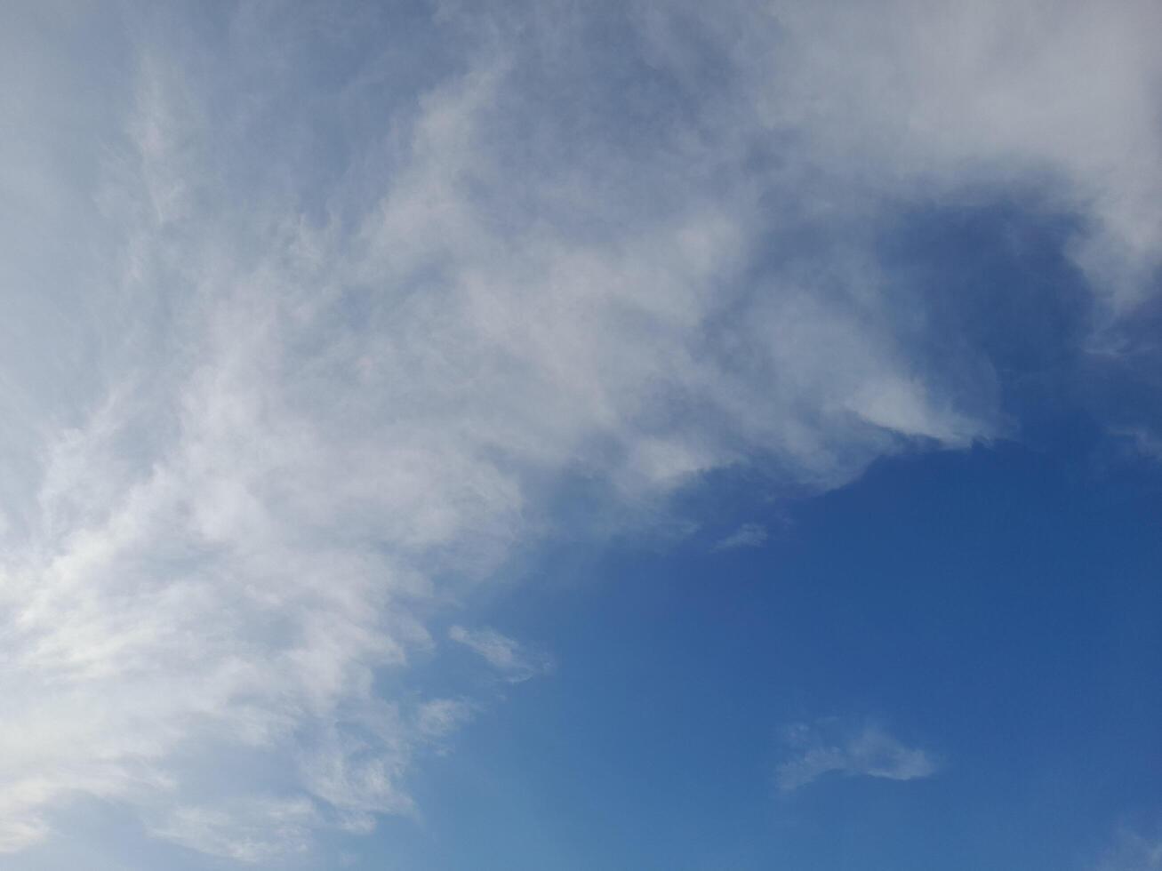 Clear blue sky with soft, wispy white clouds creating a calm and peaceful atmosphere, ideal for nature and outdoor themed designs photo