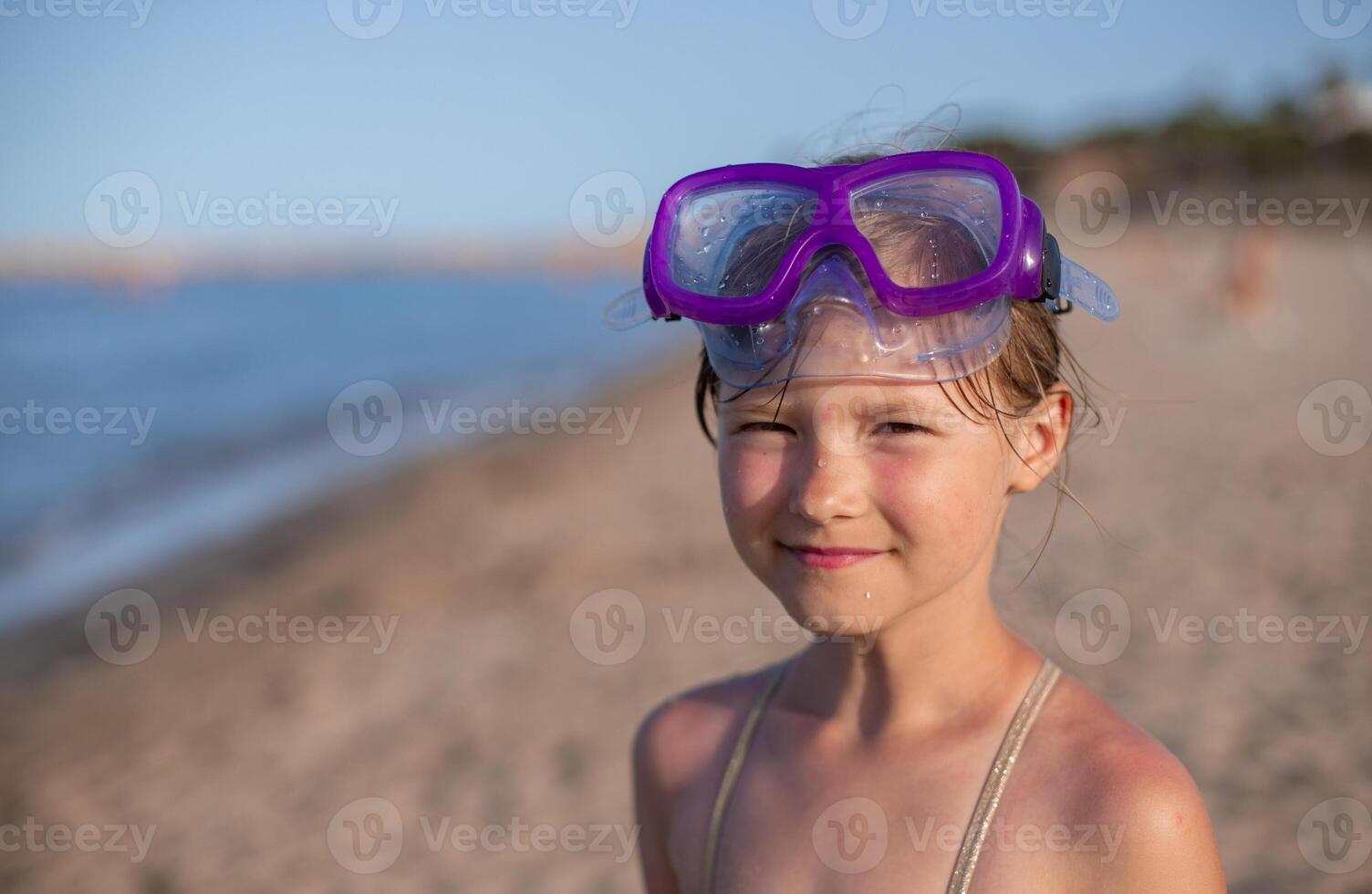 Young girl wearing snorkeling goggles at sunny beach. photo