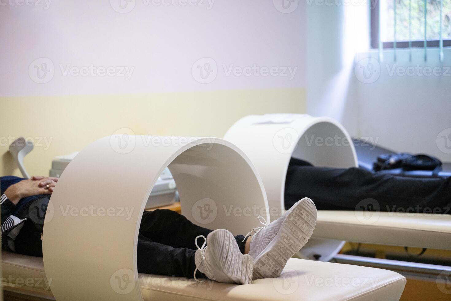 Magnet Therapy Procedure.Patients lying down with legs inside circular magnetic therapy devices during a physiotherapy session. photo